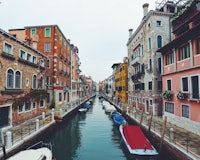 boats are docked in a canal in venice, italy